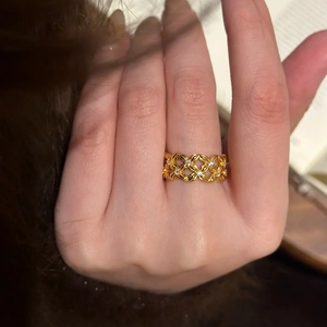 Detail of vintage gold plated hollow cross ring with sparkling zircon stones on finger
