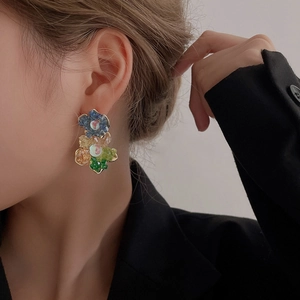 Détail macro de grandes boucles d'oreilles fleur en cristal coloré portées par un mannequin