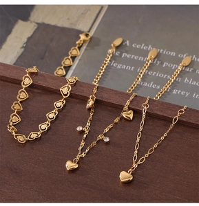 Detail shot of four gold titanium heart anklets with zircons on a dark wood surface