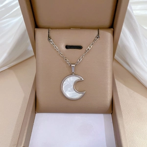 Macro shot of silver titanium moon necklace with shell inlay inside a jewelry box