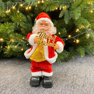Close-up of electric Santa figurine holding a golden Merry Christmas sign with warm lights