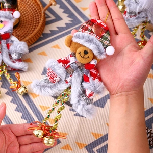 Detail of plush Christmas bear ornament with plaid hat and golden bells on legs