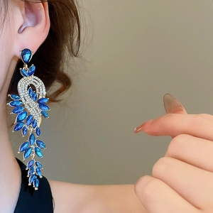 Détail de boucles d'oreilles pendantes en cristal bleu avec pampilles en diamants