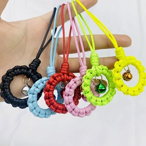 Hand holding colorful bohemian woven wristlet keychains with small metal bells
