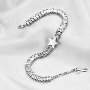 Detailed shot of silver star charm bracelet with rectangular zircon stones on silk