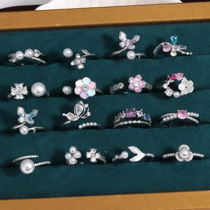 Collection of 16 styles of butterfly and floral zircon rings on green velvet tray