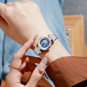 Elegant silver mesh band watch with dark mother-of-pearl dial worn on woman's wrist