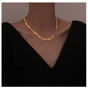 Detailed view of intertwined gold snake chain necklace on collarbone with twisted links
