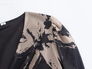 Détail de l'imprimé beige abstrait sur maille noire avec coutures et étiquette de taille S