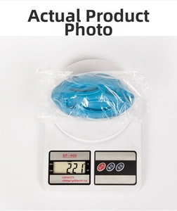 Blue squeaky rubber dog football toy on an electronic scale showing 221g product weight