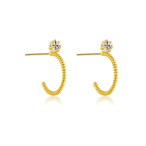 Detailed view of twisted gold C-shaped hoop earrings with a sparkling zircon inlay