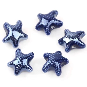 Close-up of five deep blue starfish ceramic beads with glazed texture for DIY jewelry
