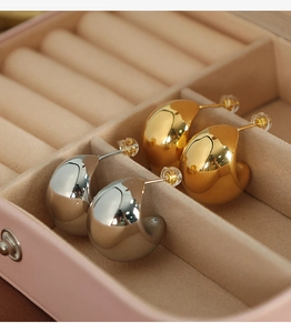 Polished gold and silver waterdrop earrings displayed in a pink velvet jewelry box