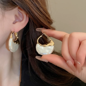 Artistic gold geometric earrings with pearl white texture inlay on neutral background