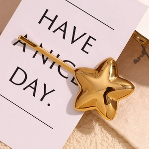 Detailed view of a 18K gold-plated star hair clip on a decorative white card