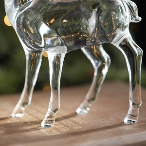 Elegant transparent acrylic reindeer figurine standing on a vintage book for Christmas decor
