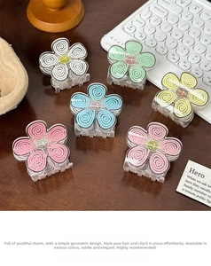Detailed view of flower-shaped hair clips in six macaron colors on a wooden surface