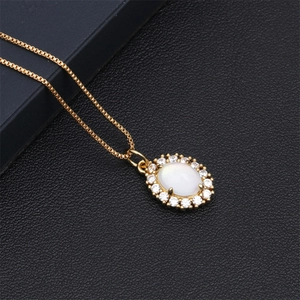 Detailweergave van een goudkleurige ketting met ovale witte hanger en zirkonia inleg