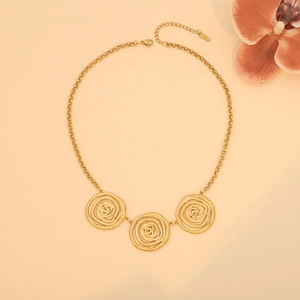 Detailed view of golden irregular swirl pendants on a stainless steel necklace chain