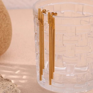 Detail of 18K gold plated stainless steel tiered geometric tassel earrings on glass