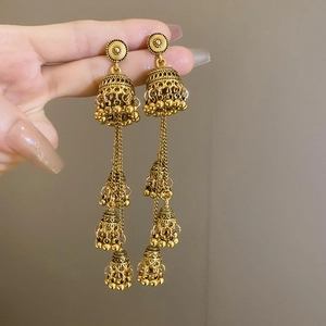 Close-up of vintage golden multi-layer Jhumka earrings with bell tassel details