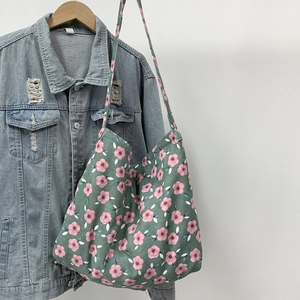 Detailed view of the dark green floral canvas tote bag hanging on a denim jacket hanger