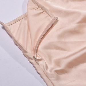Détail de la fermeture éclair invisible sur une robe en satin champagne élégante