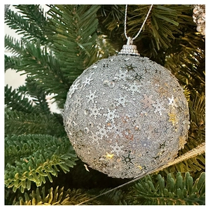 Close-up of a silver glitter Christmas ball with snowflake sequins hanging on a tree