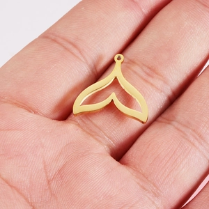 Macro shot of a golden mermaid tail pendant on a palm for DIY necklace making