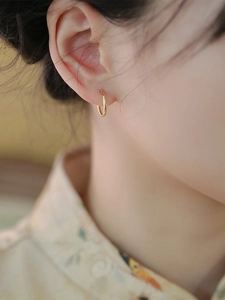 Detail view of a 10mm gold hoop earring in 18K minimalist style on model ear