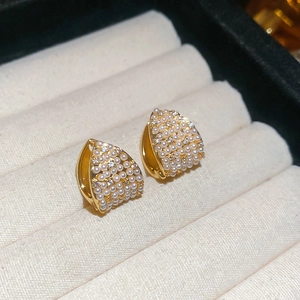 Close-up of elegant gold hoop earrings with shimmering pearls and zircon in a jewelry box