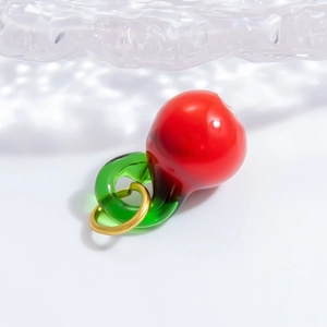 Macro shot of cherry pendant with red glossy surface and green stem for DIY jewelry