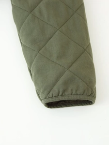 Detail shot of army green quilted cotton jacket showing twill texture and diamond stitching