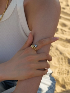 Outdoor shot of two-tone teardrop open ring on model finger against beach background