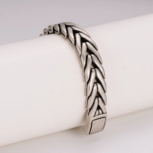 Vintage silver stainless steel woven bracelet with geometric links on display