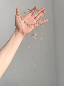 Detail of layered gold necklaces with star charms and a crystal-encrusted cross pendant