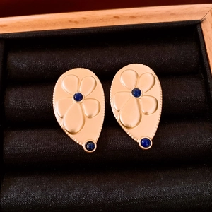 Close-up of golden floral drop earrings with blue stones on black velvet background