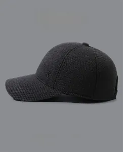 Detail of dark grey winter baseball cap showing tweed texture and metal T emblem