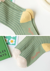 Detail of green striped cotton socks with orange embroidery and yellow contrast heel