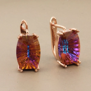 Luxury rose gold earrings featuring radiant gradient crystal stones in a studio setting
