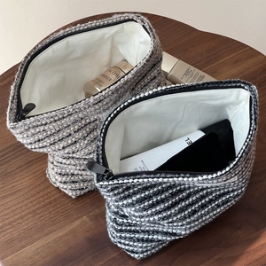 Close-up of thick tweed makeup bag showing spacious interior with skincare items