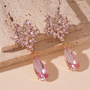 Close-up of pink crystal teardrop earrings with floral design on a natural stone base