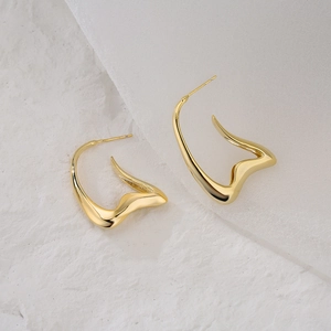 Abstract curved 18K gold-plated irregular geometric earrings on a white textured background