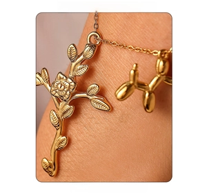 Detail of 18K gold-plated necklace with vintage cross rose and balloon dog pendants