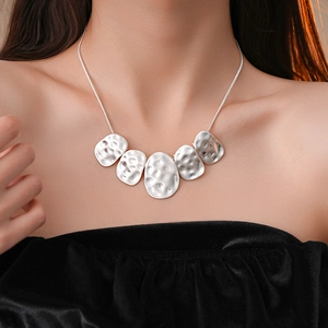 Close-up of silver irregular hammered oval pendant necklace on black velvet dress