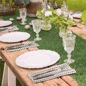 Detail of artificial grass table runner on a vintage wooden table for garden party decor