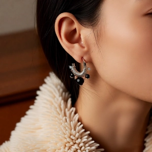 Detailed close-up of vintage silver C-shaped wrap earrings with black glass beads