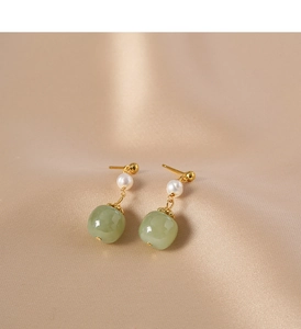 Close-up of vintage gold earrings with round white pearls and green jadeite drops