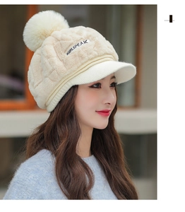 Detailed texture of beige winter knit hat with plush faux fur pompom and curved visor