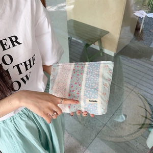 Detailed close-up of a blue floral cotton makeup pouch with Sozakka label in hand